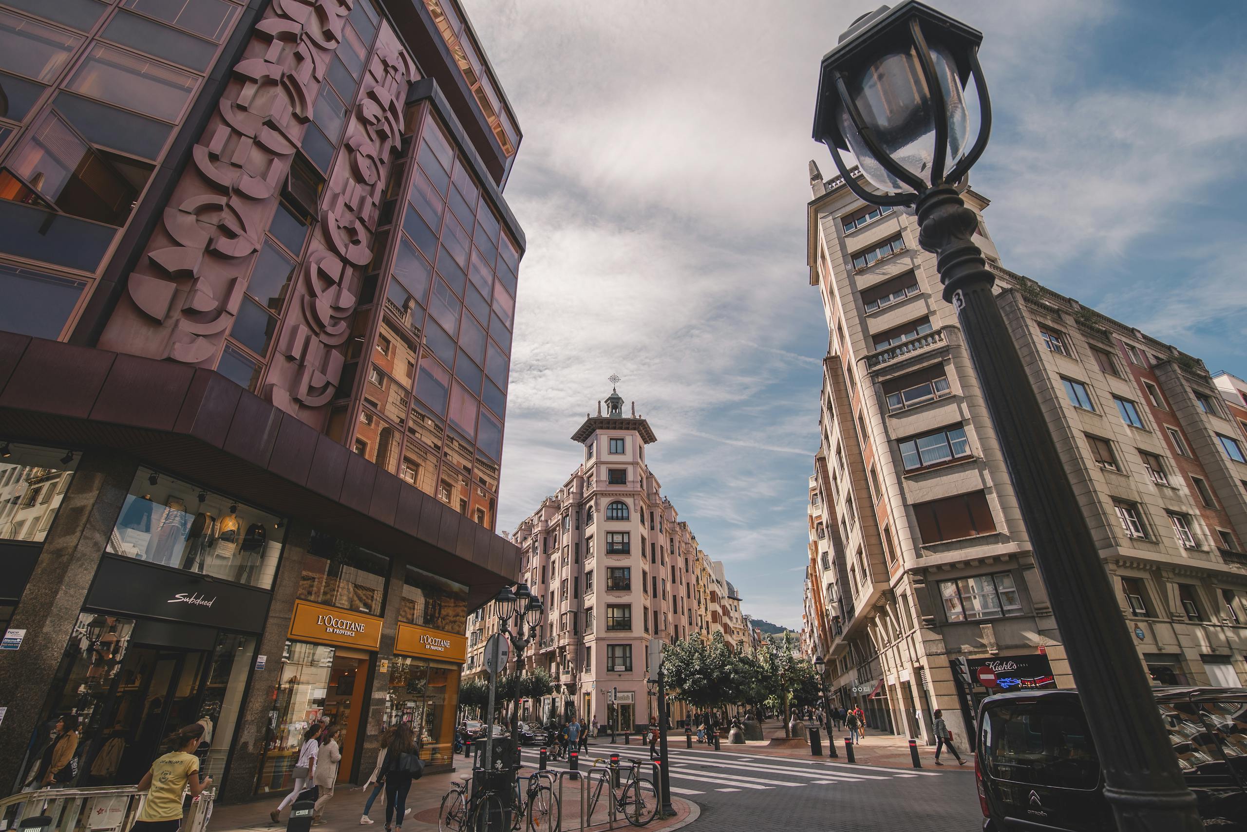 A bustling urban street in Bilbao, Spain, showcasing unique architectural styles and vibrant city life.